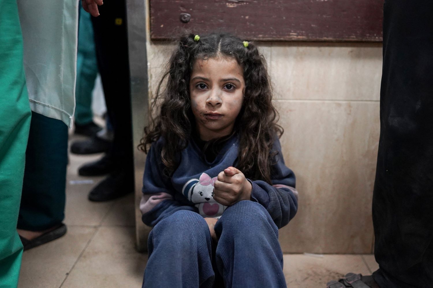 فتاة تجلس على أرضية غرفة الطوارئ في مستشفى شهداء الأقصى في دير البلح (تصوير: فرانس برس)